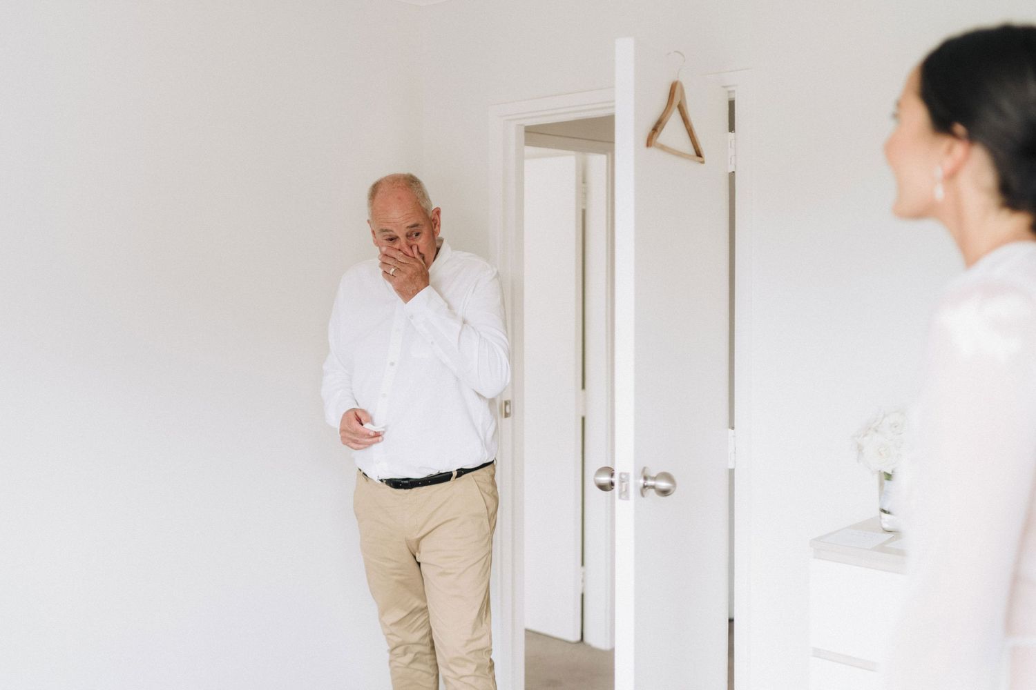 Two people having a conversation in a bright white hallway.