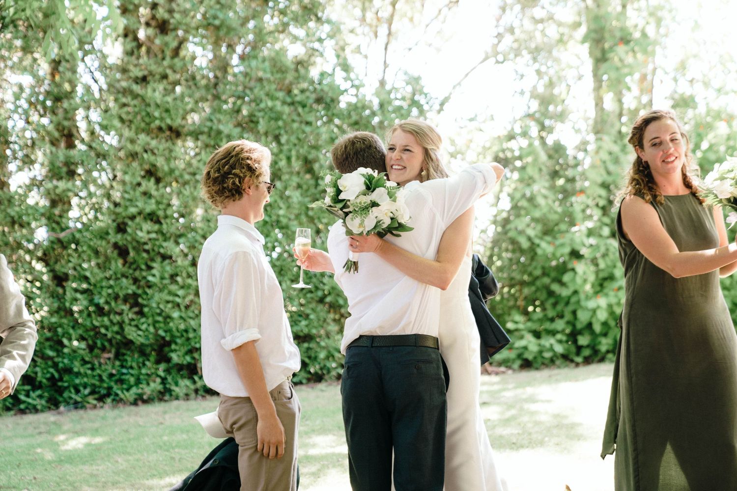 Wedding party members sharing a joyful moment in a garden setting.