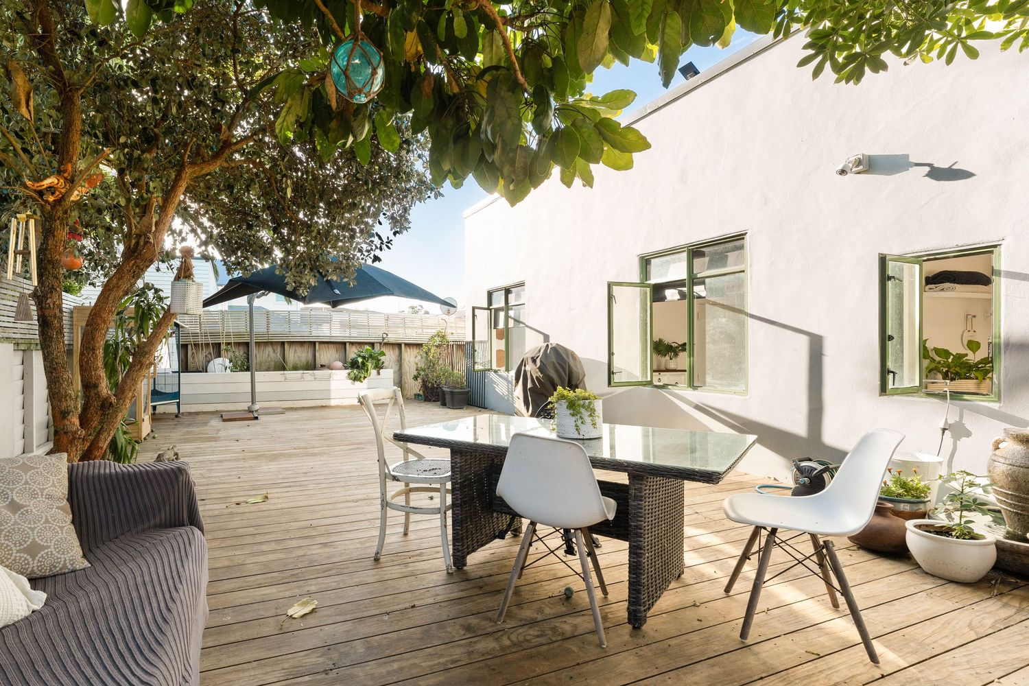 Spacious deck with modern outdoor furniture and natural shade from overhanging trees.