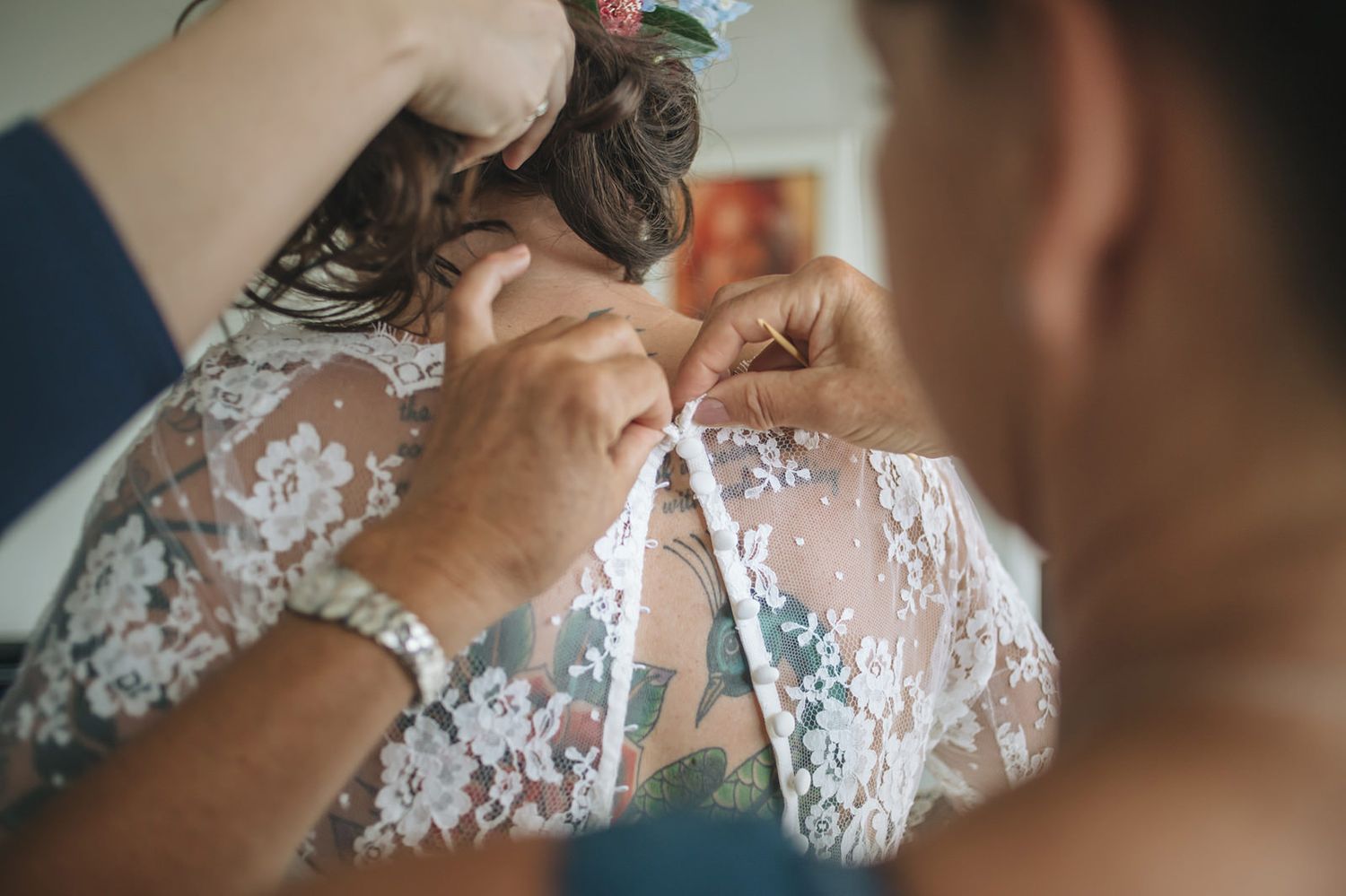 A blurred sequence of photos showing someone applying finishing touches to a delicate white lace wedding dress.