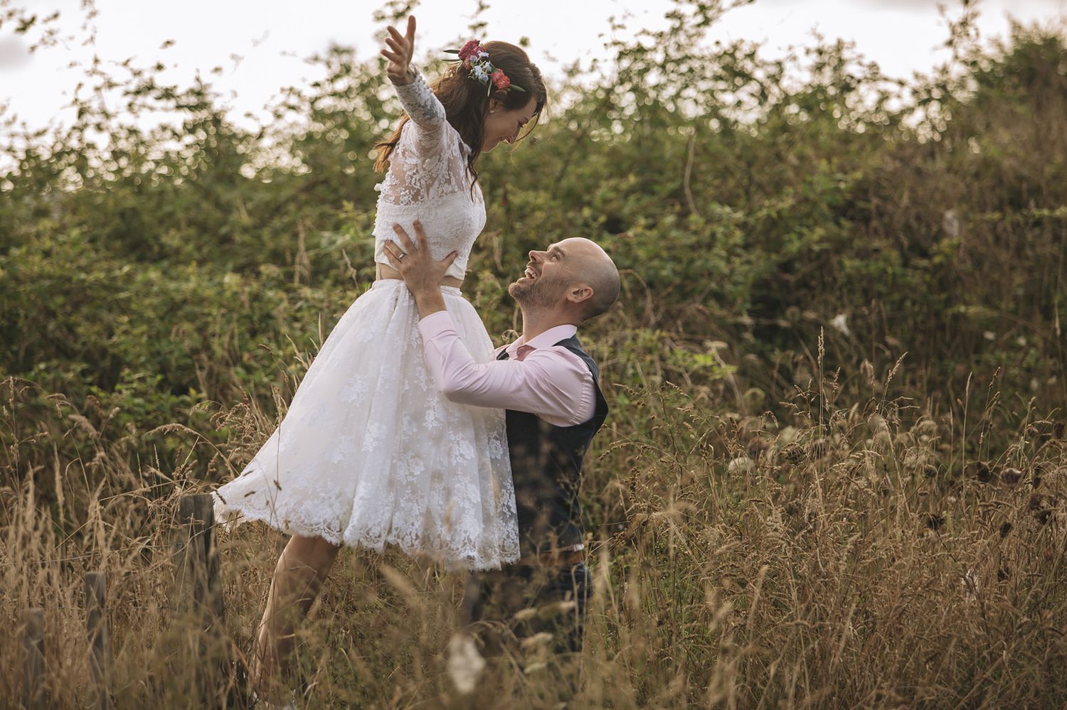 Romantic outdoor photo session of couple surrounded by sunlit grasses and natural scenery.