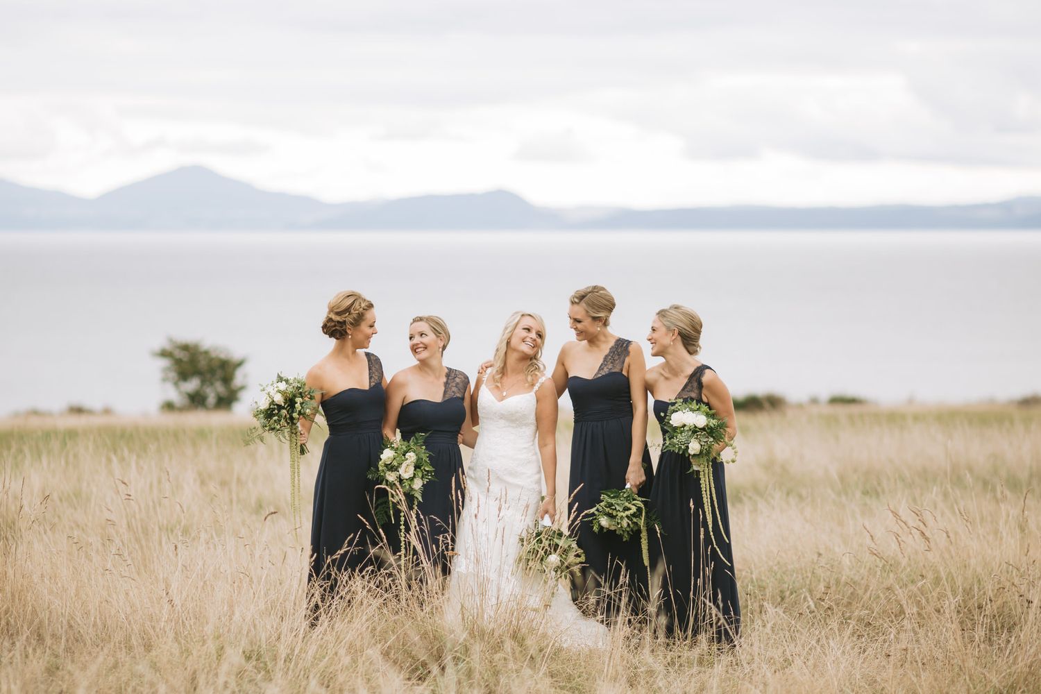 Group stands together in a golden field with mountains in the distance on a sunny afternoon.