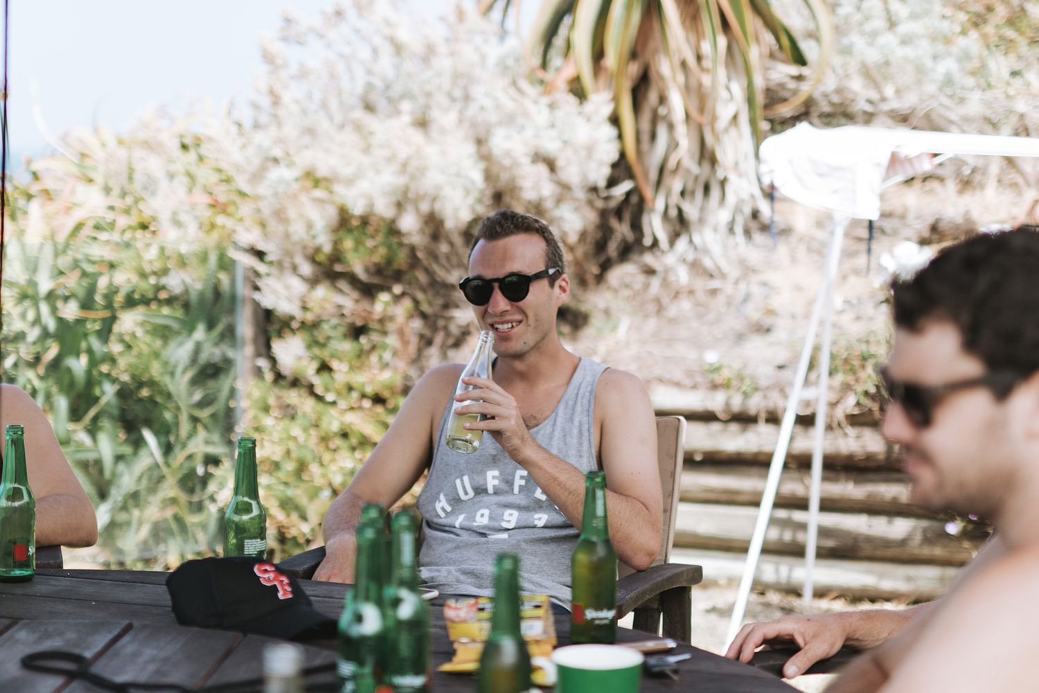 A casual gathering of individuals sitting at an outdoor dining table enjoying food and drinks together.