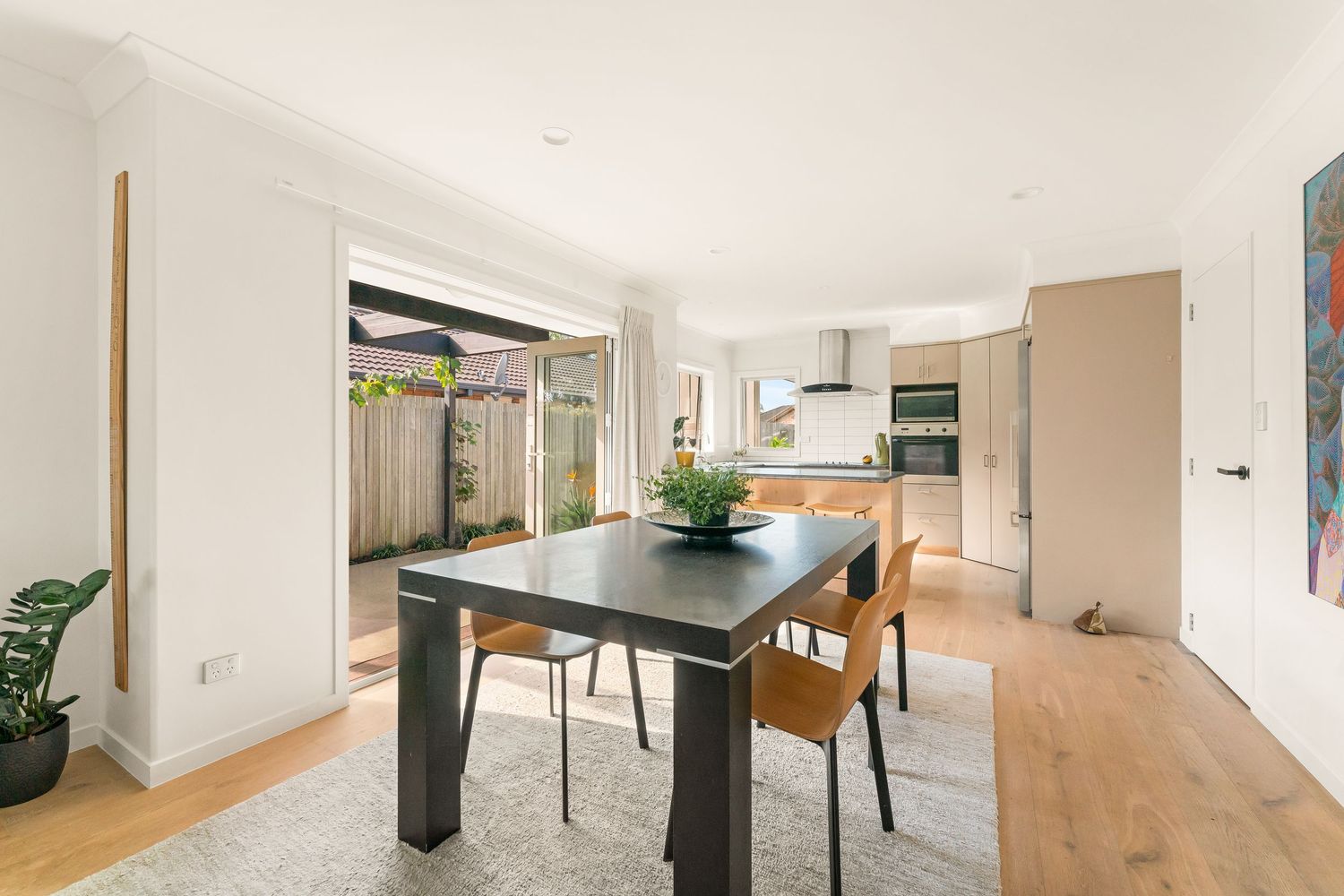 Modern open-plan apartment interior with white walls, hardwood floors, and minimalist furniture throughout.