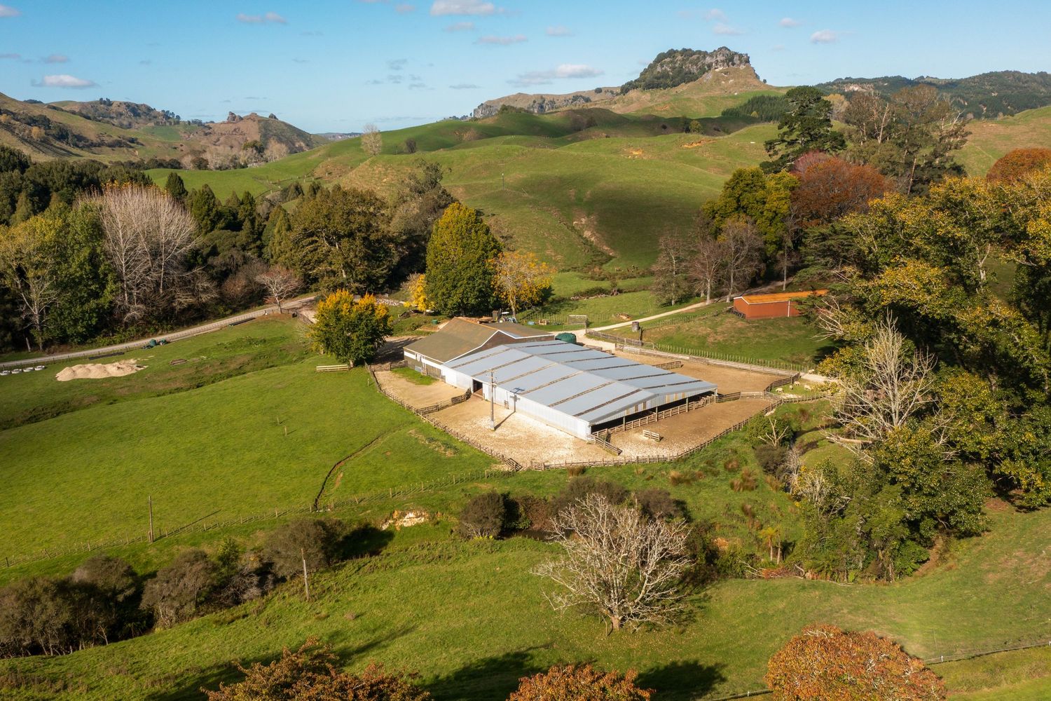 Aerial view of large covered equestrian arena surrounded by green pastoral hills.