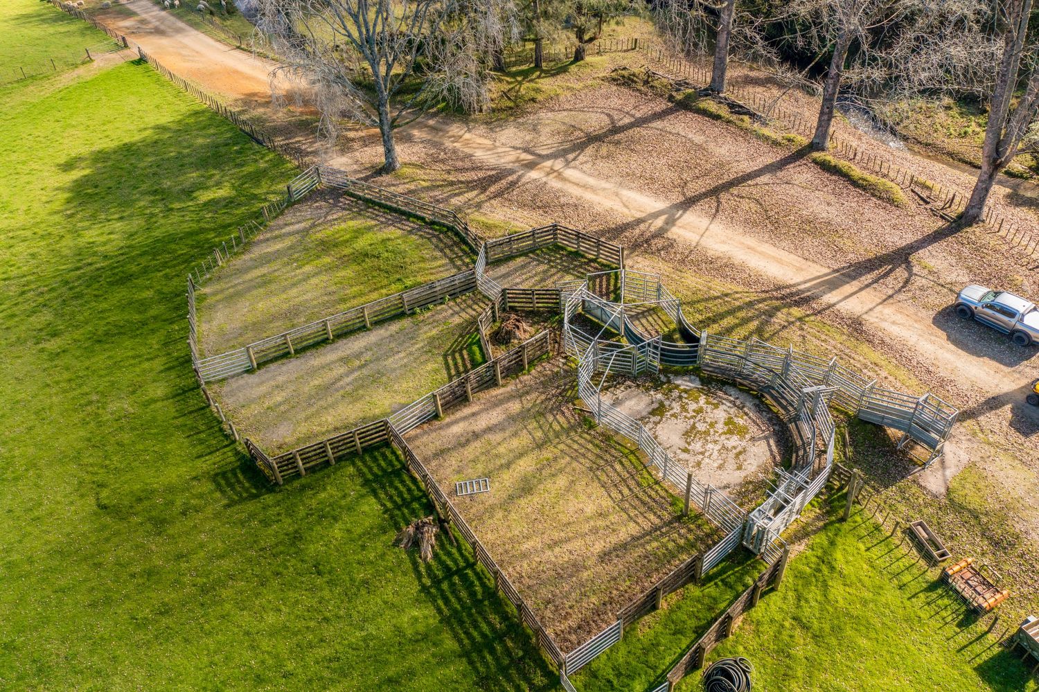 Aerial view of horse paddocks and training areas with wooden fencing on green pastureland.
