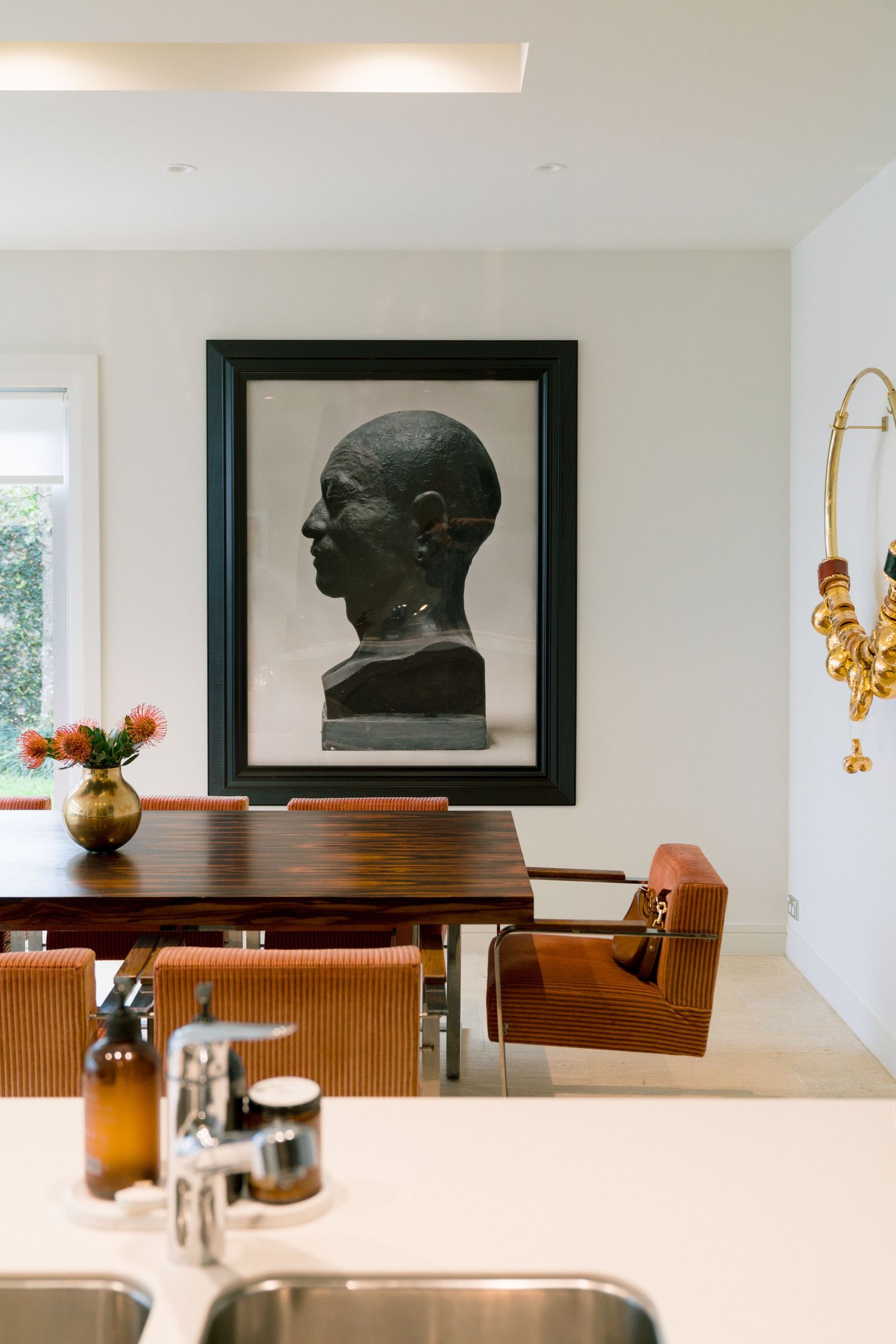 Modern minimalist interior with wooden table and decorative sculptures displayed against a white wall.