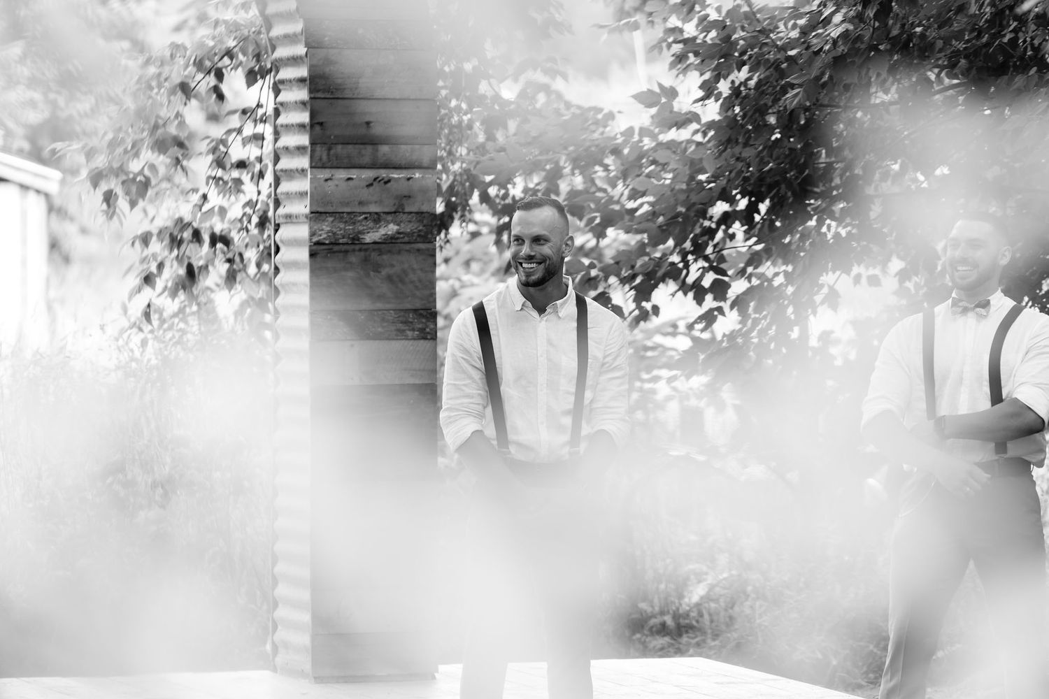 Black and white artistic wedding photograph with soft focus elements creating a dreamy ethereal effect in an outdoor setting.