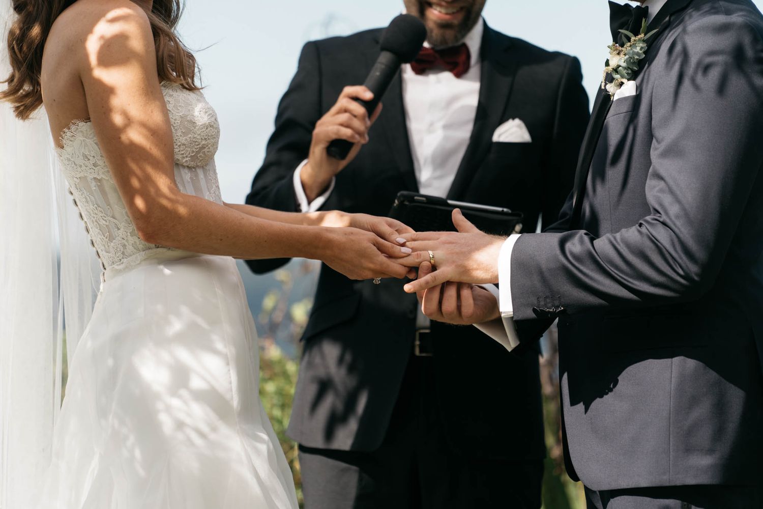 A couple shares an intimate moment during their wedding ceremony while reading from paper notes in a scenic setting.