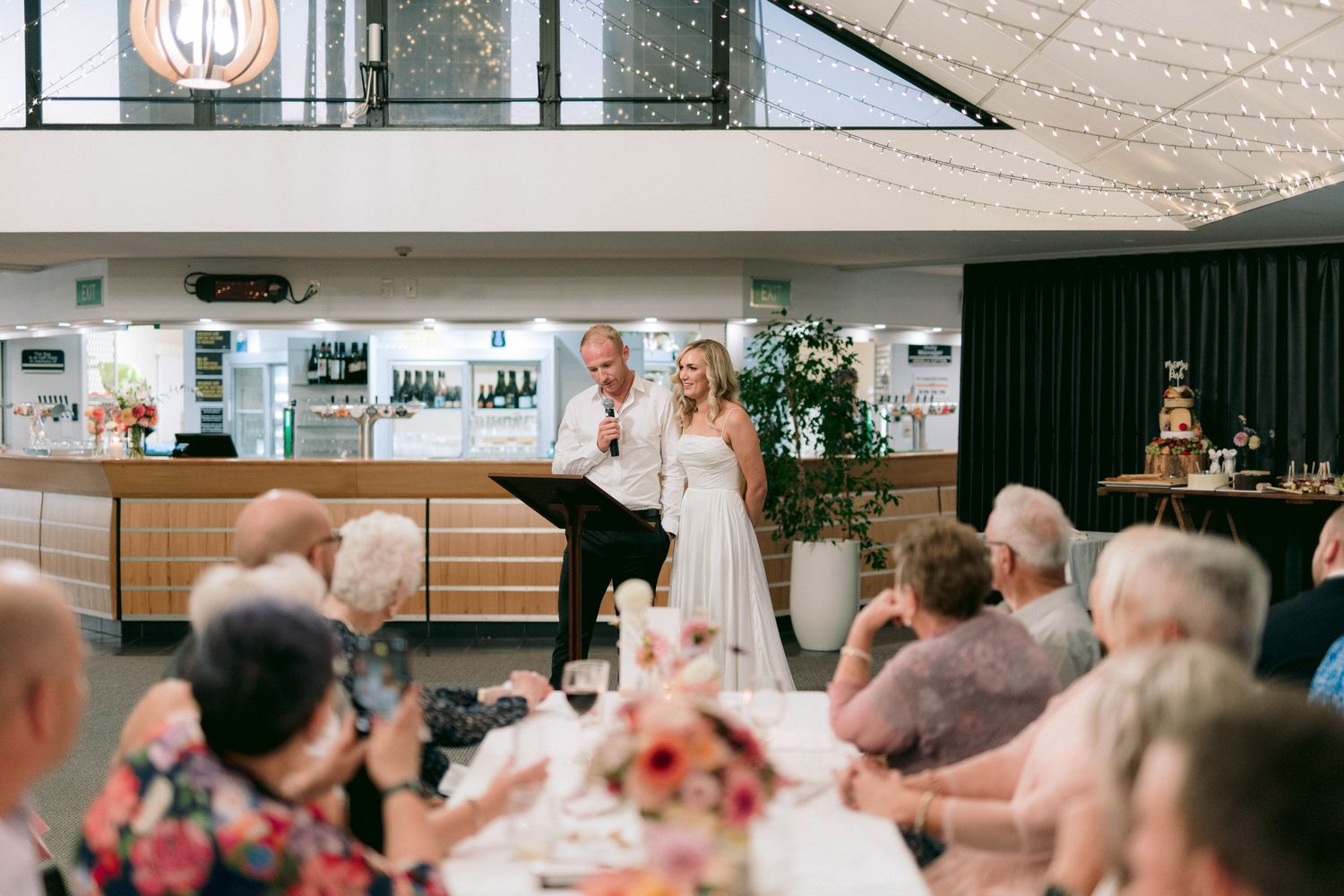Wedding reception venue with guests seated at tables in a large indoor space.