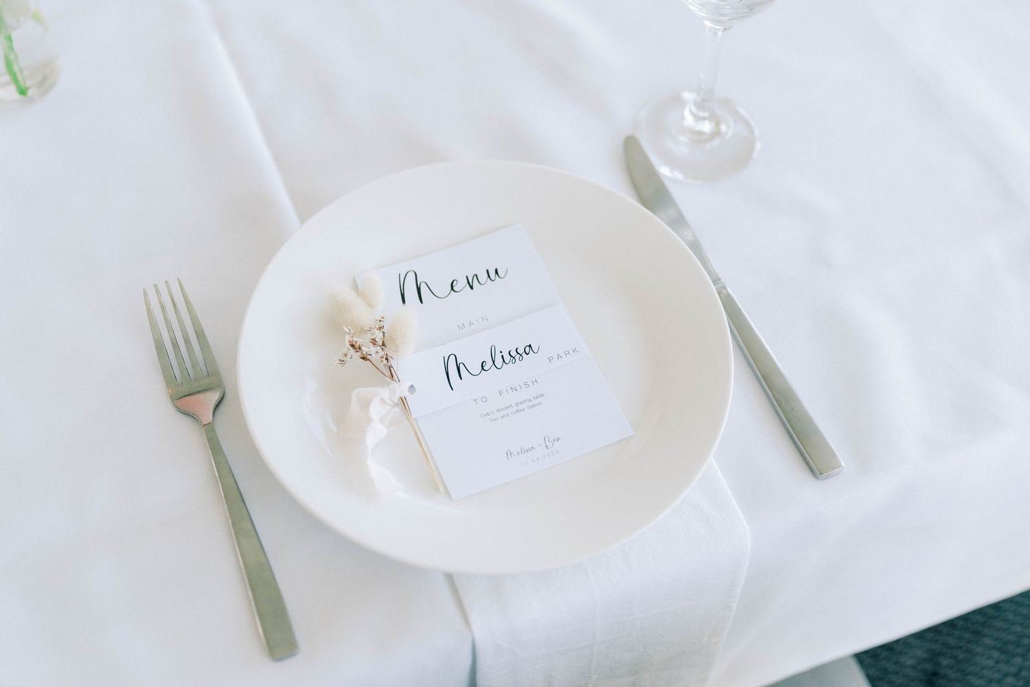 White place settings and elegant tableware arranged on a minimalist wedding reception table.