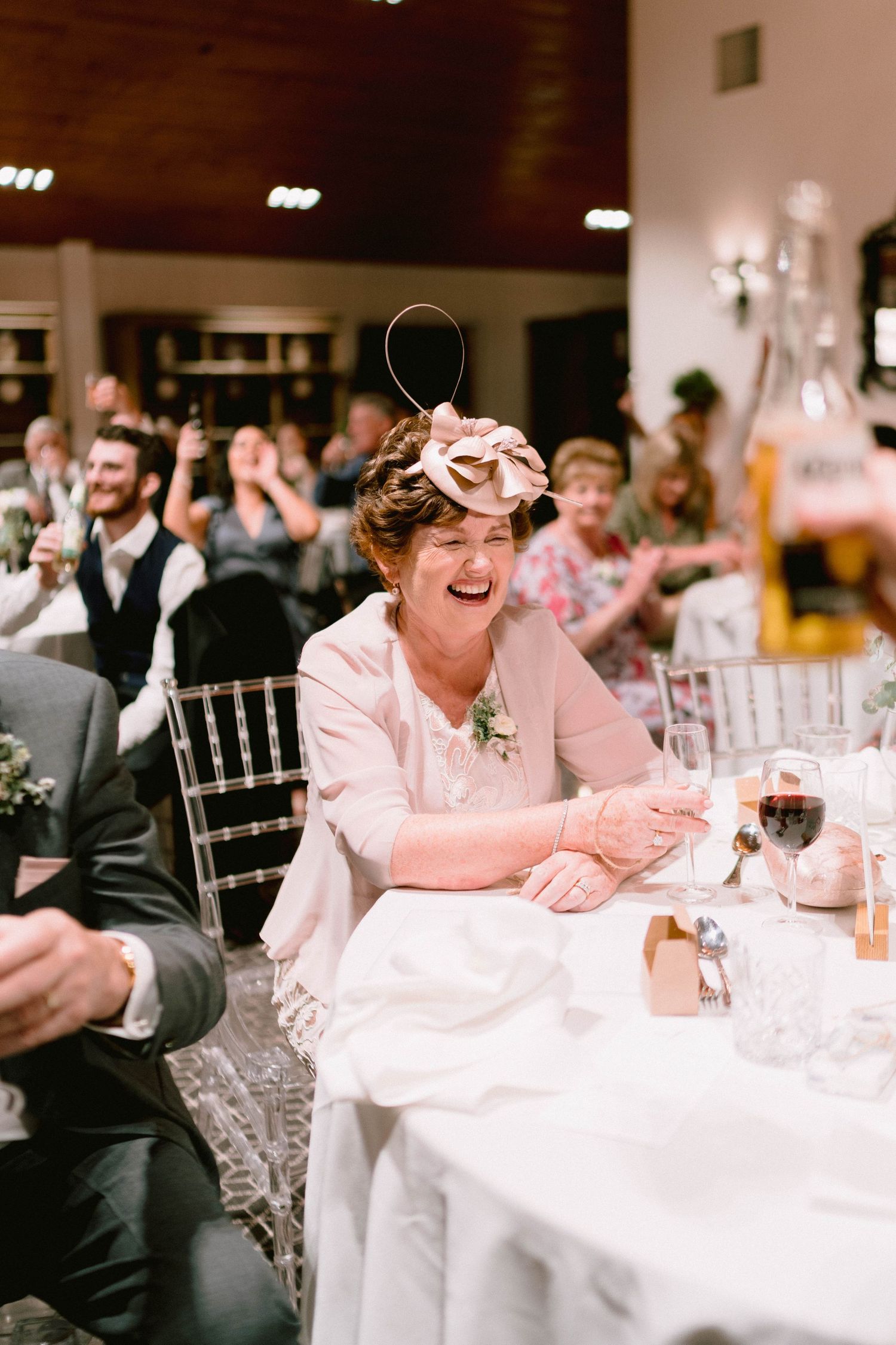 A wedding guest laughs joyfully at a reception table decorated with formal place settings.