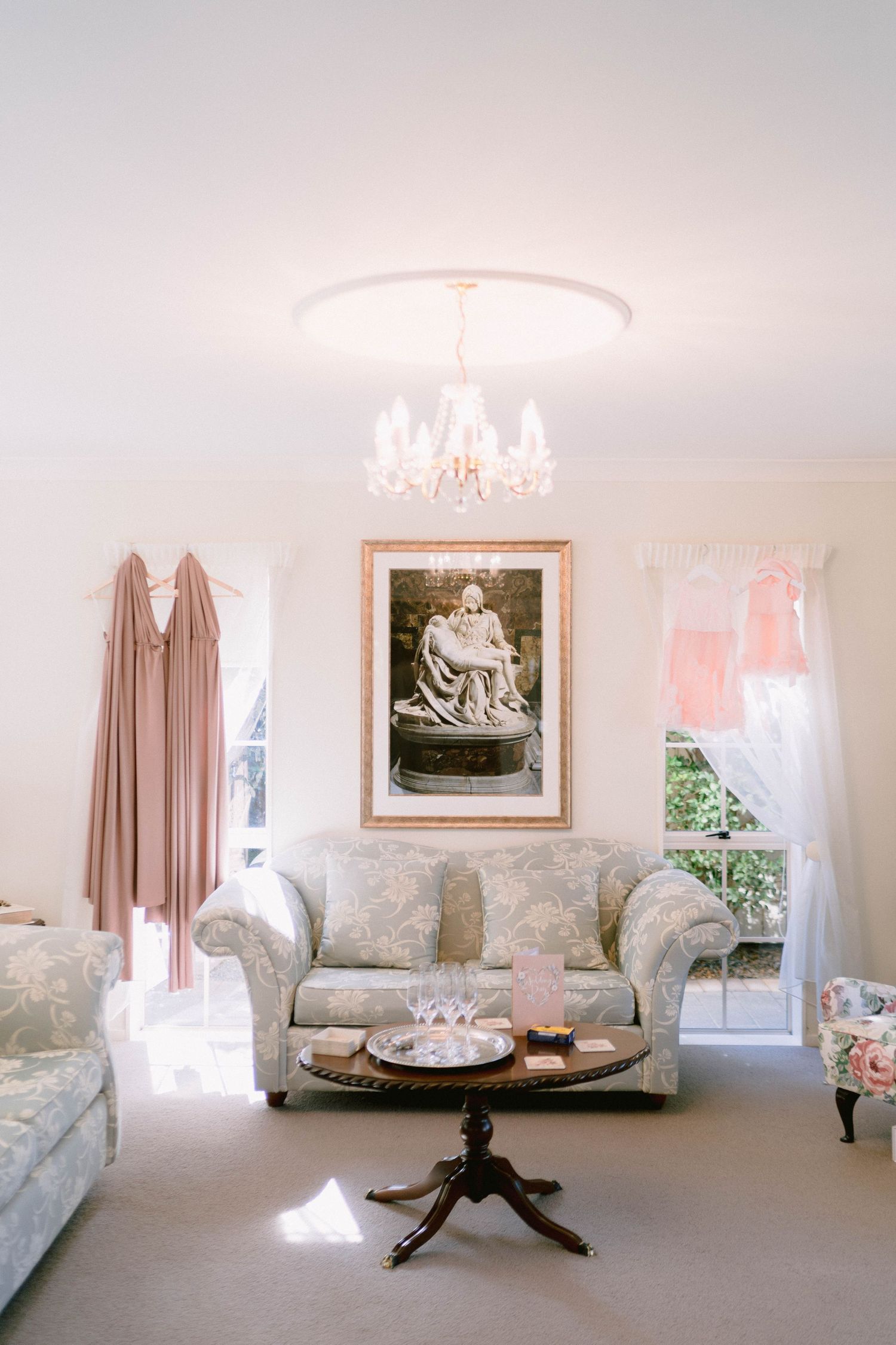 Three views of an elegant white living room with floral print sofa, artwork and dark wood coffee table on light carpet.