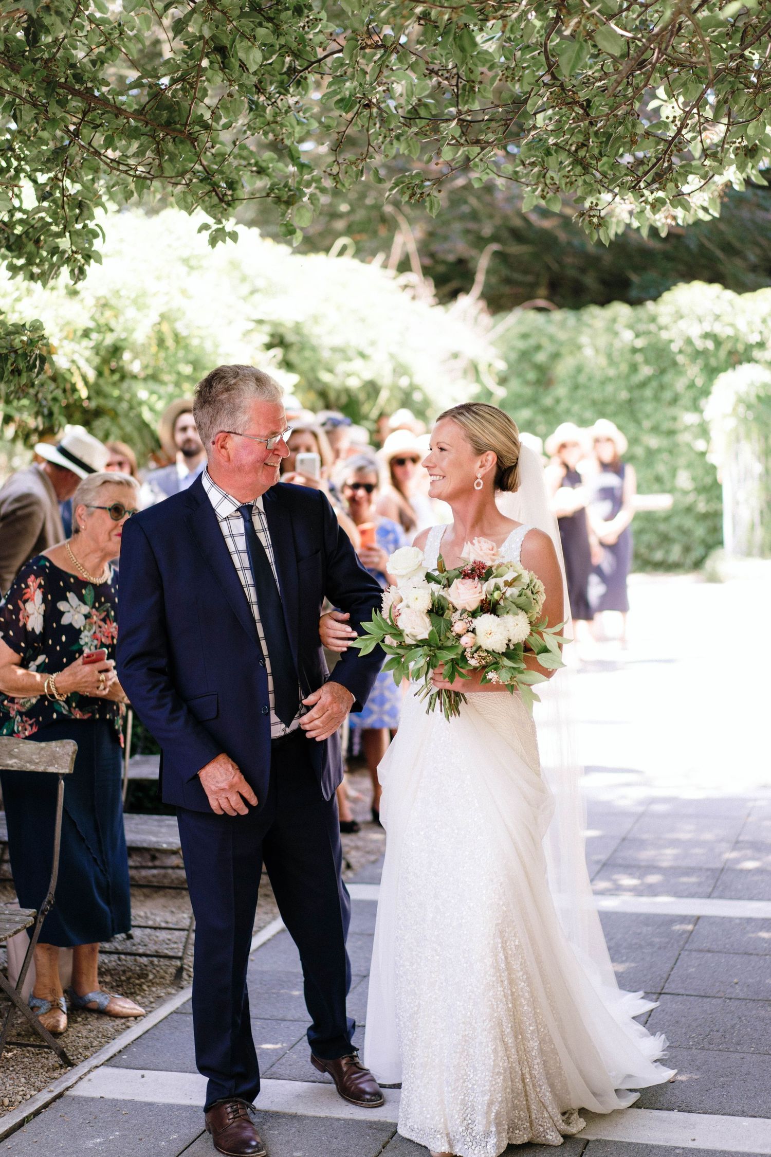 An outdoor wedding ceremony under tree branches with guests gathered to celebrate the special day.
