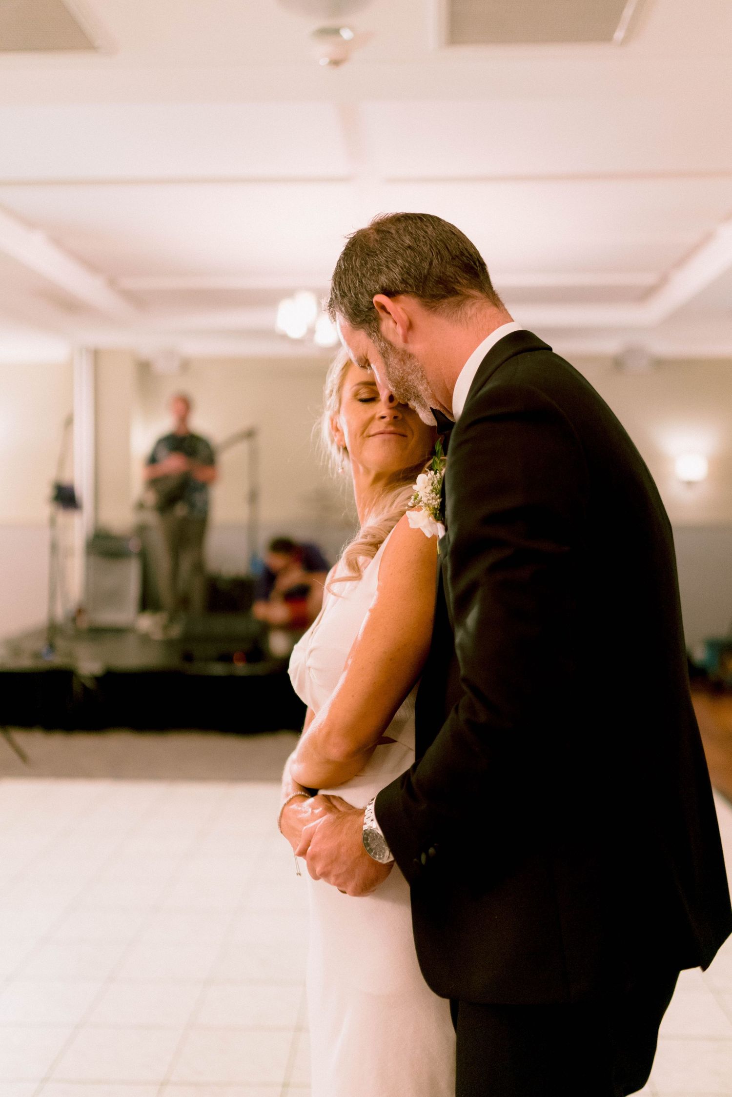A couple shares an intimate slow dance moment at their wedding reception in an elegant ballroom.