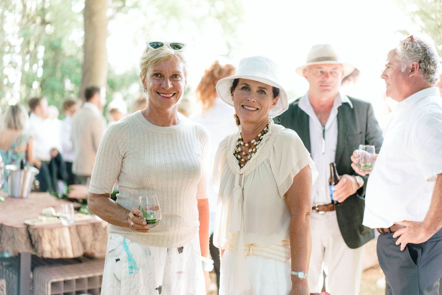 Guests in light summer clothing socializing at an outdoor garden party.