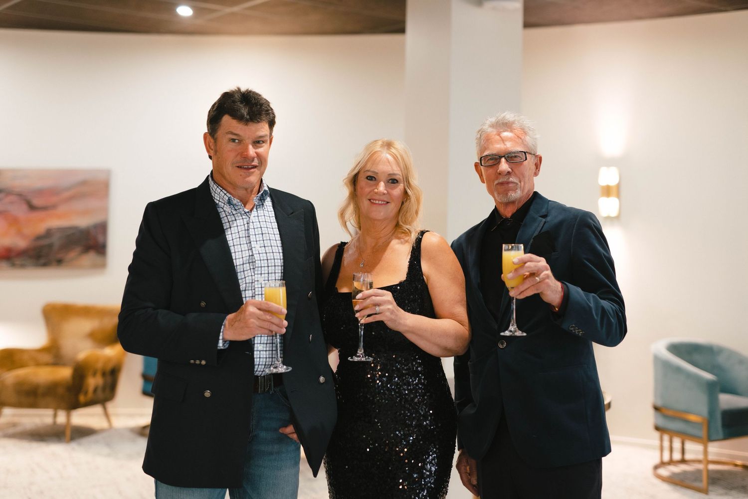 Three guests enjoy cocktails while socializing at an art gallery reception.