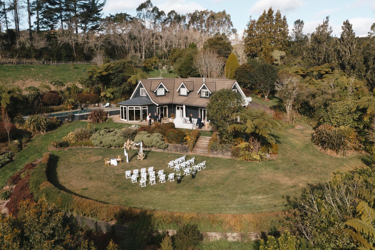 Panoramic aerial view of a charming countryside estate with white buildings nestled among autumn trees and rolling hills.