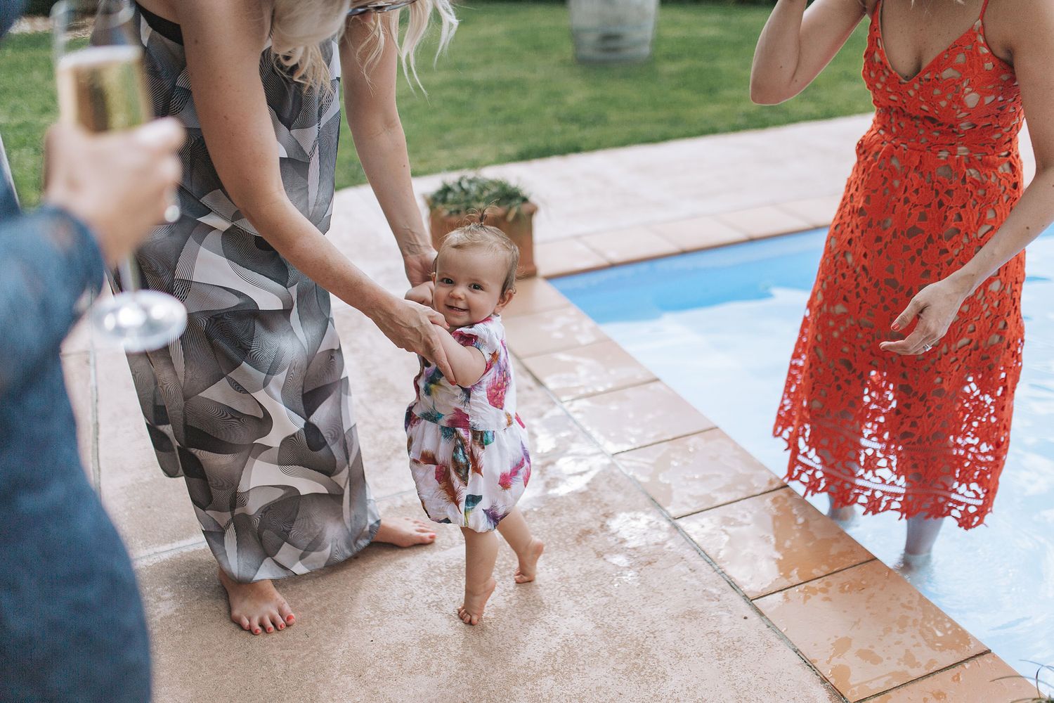 Multiple shots of someone in a red lace dress washing a small white dog at an outdoor pool area.