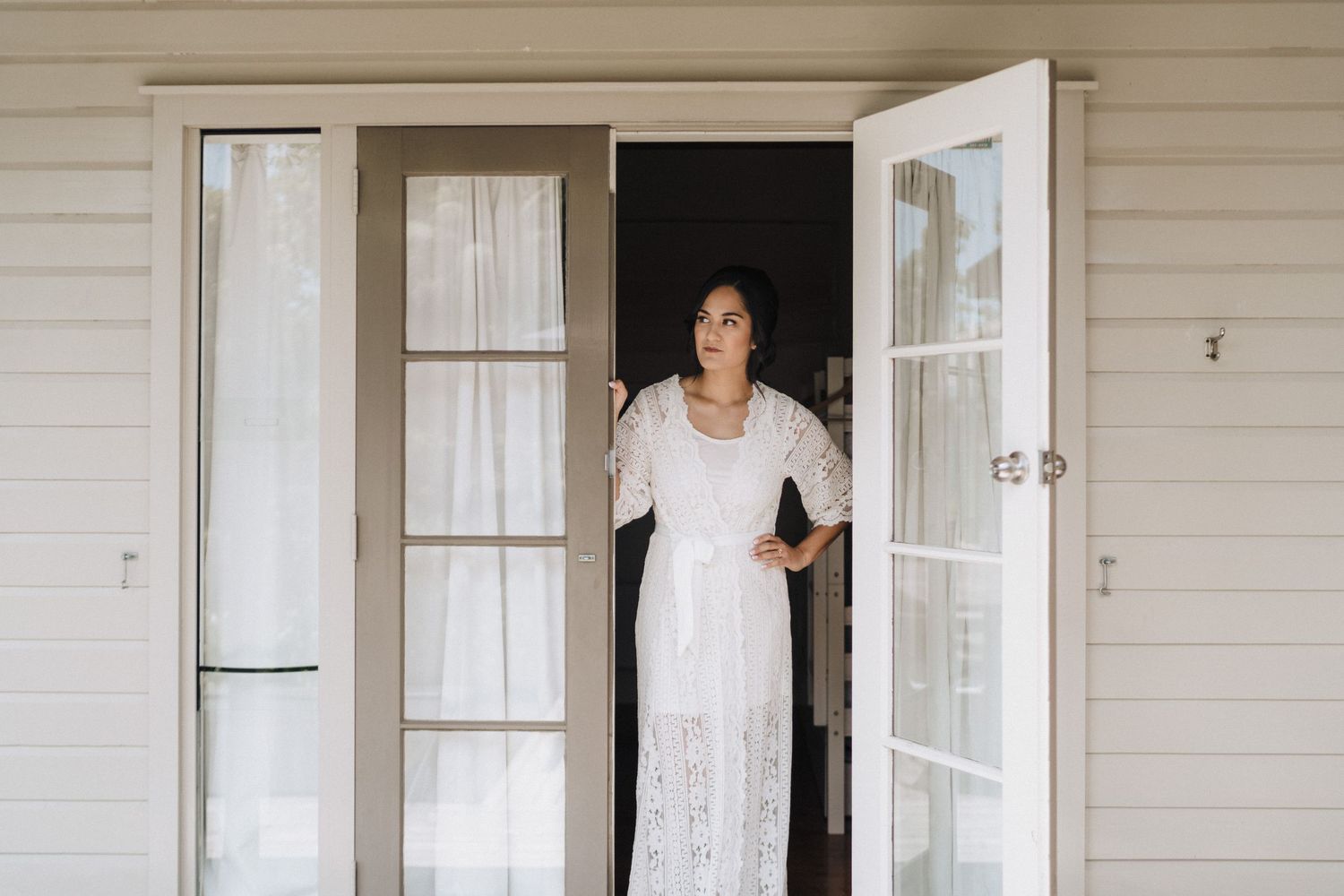 A series of people posing in doorways and entryways of a light-colored house with white trim and windows.