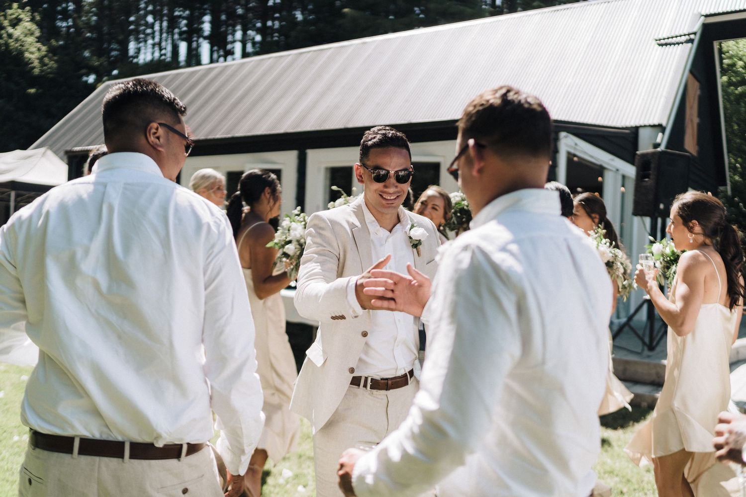 Wedding guests in casual summer attire mingle during an outdoor reception.