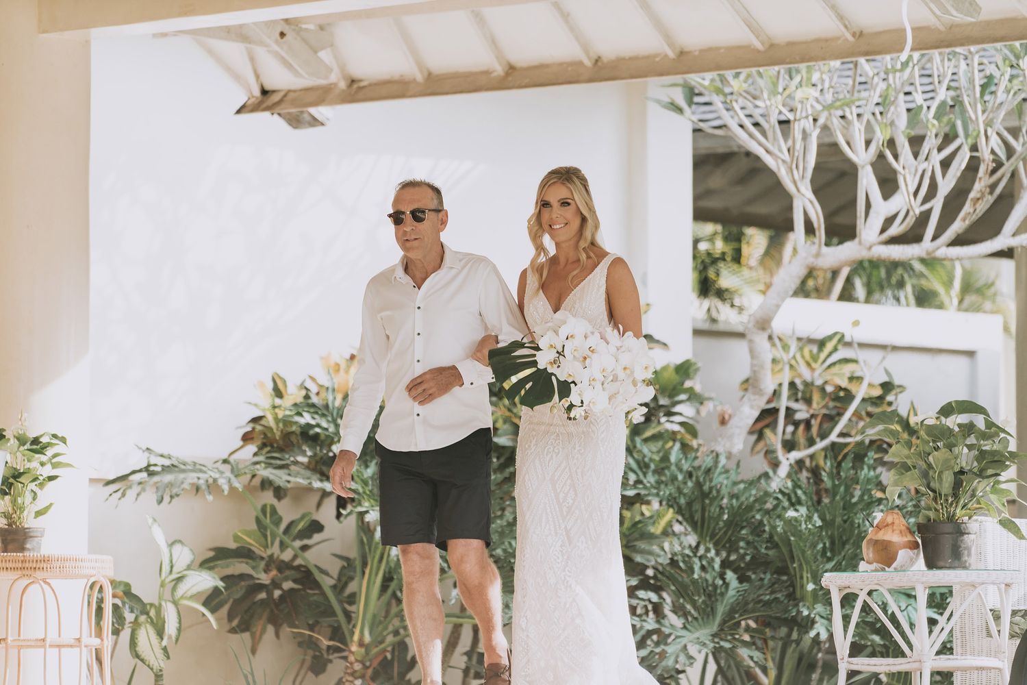 Sunlit outdoor venue with white pillars and pavilion decorated for a special event.