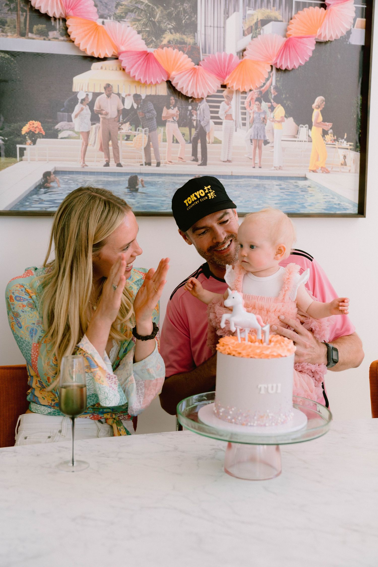 Birthday celebration with pink and peach decor featuring a white cake on a pedestal stand.