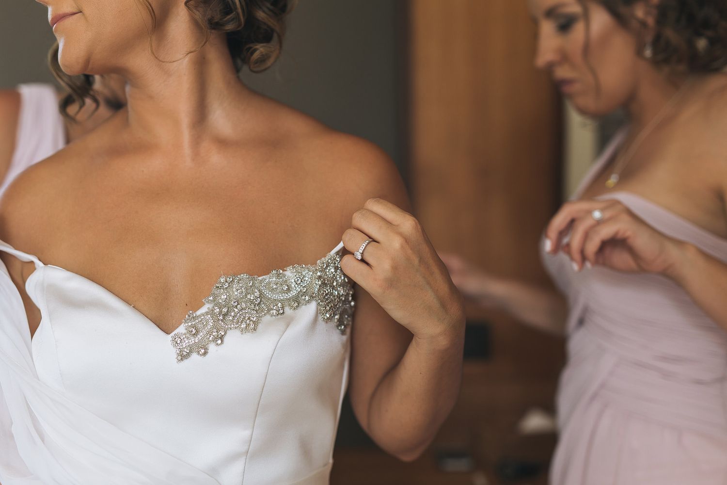 Close-up shot of intricate lace detail being adjusted on a white wedding dress.