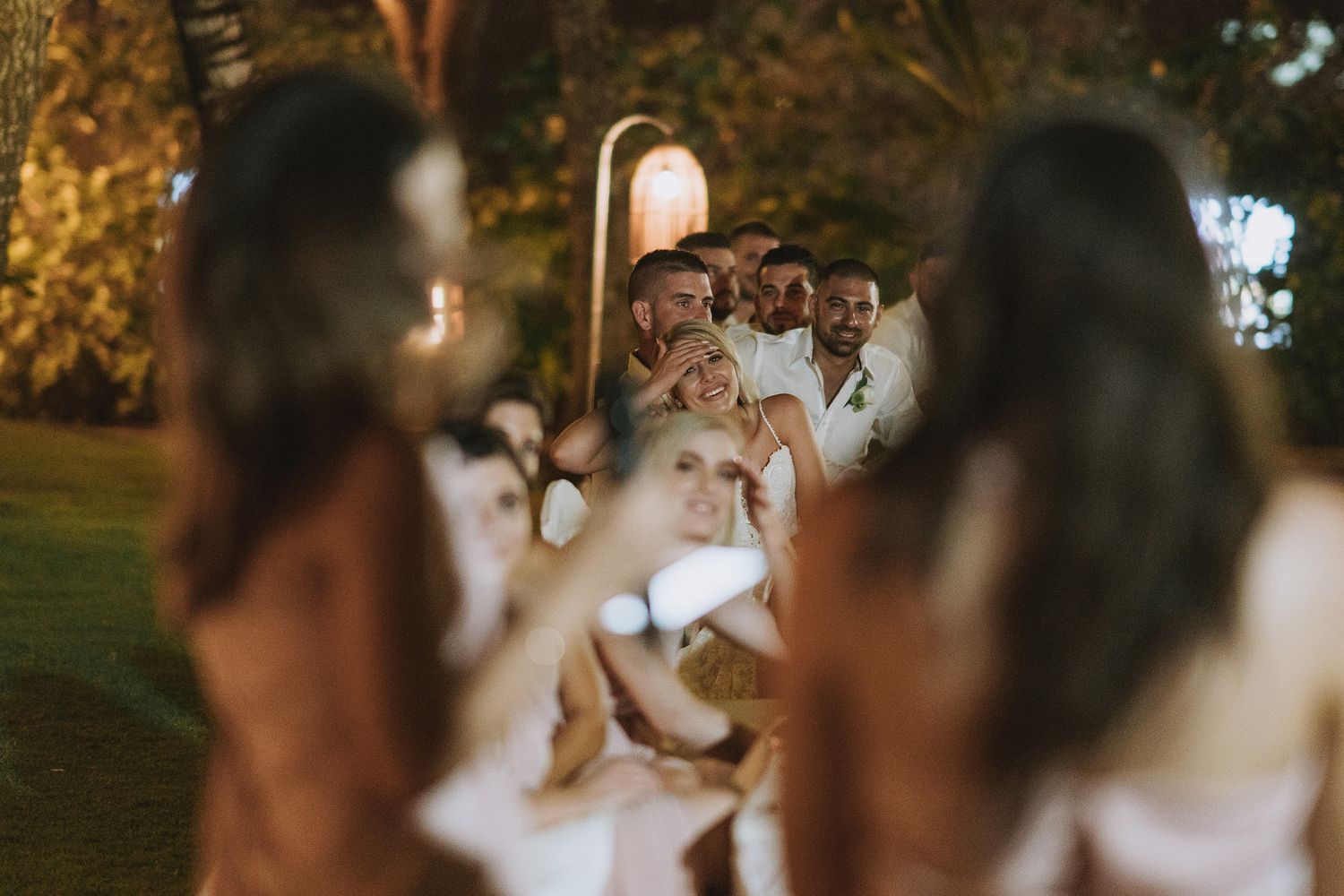 Party guests dance and celebrate at a nighttime outdoor wedding reception.