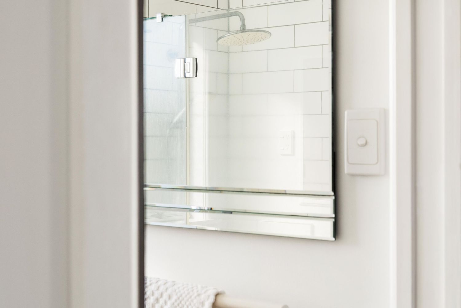 Clean white bathroom interior with frameless mirror and modern fixtures.