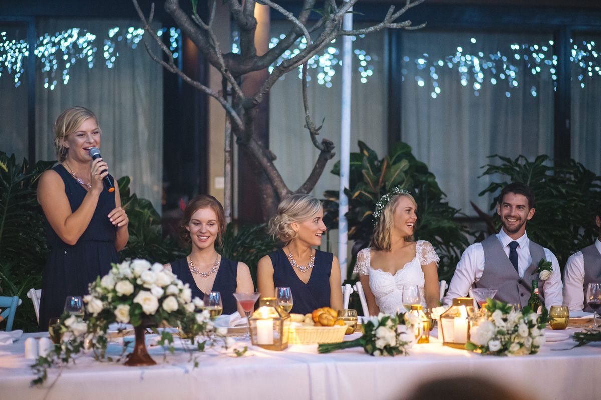 Wedding reception dinner setup with twinkling lights and elegant table decorations in evening setting.