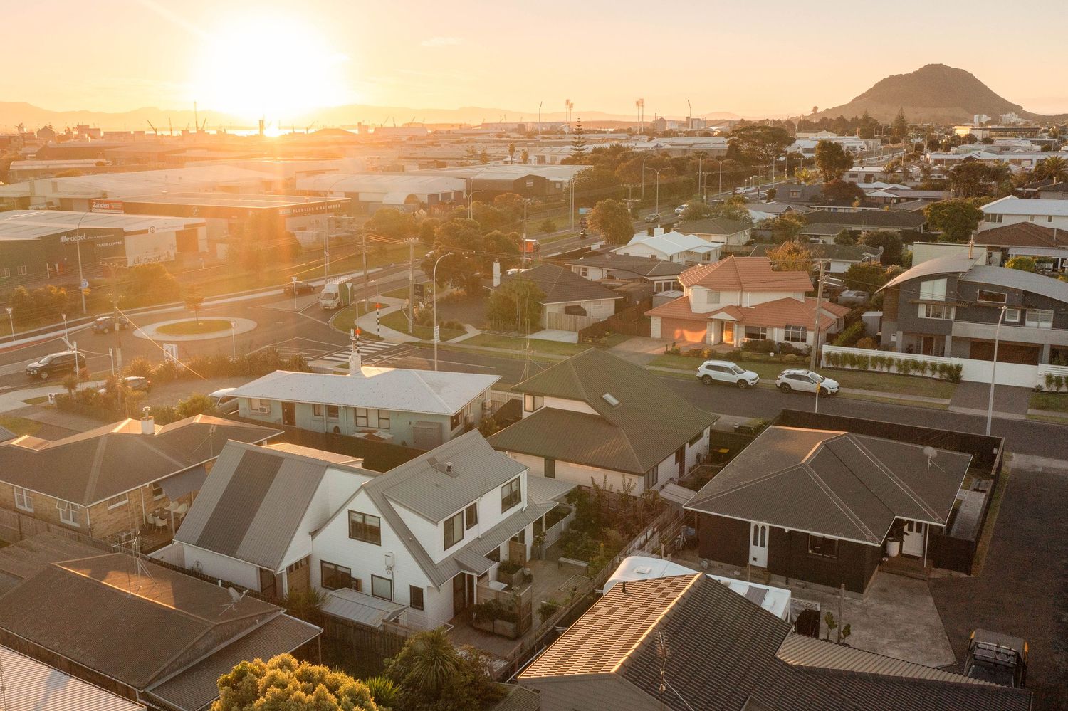 Aerial view of residential neighborhood with houses and rooftops at golden sunset in a suburban area.