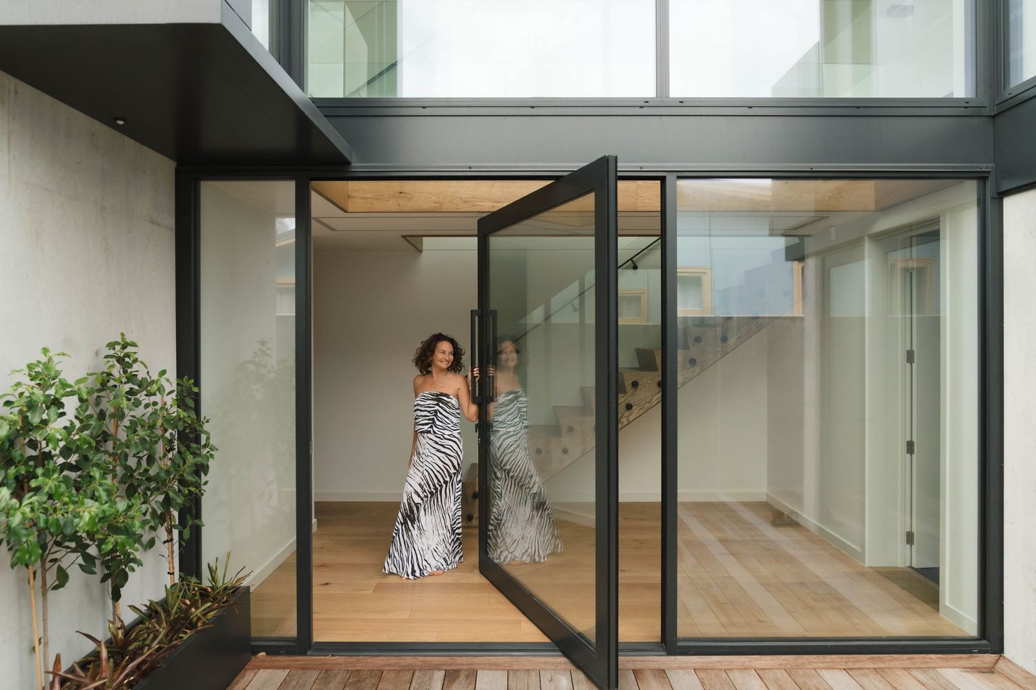 Contemporary open-concept interior with glass walls, high ceilings, and abundant natural light.