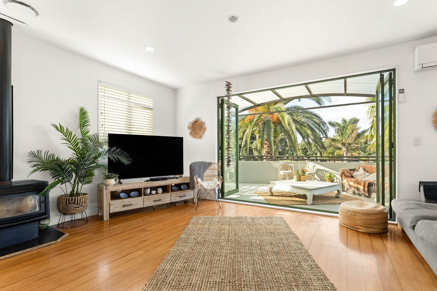 Bright open concept living room with wooden floors and large windows letting in natural light.