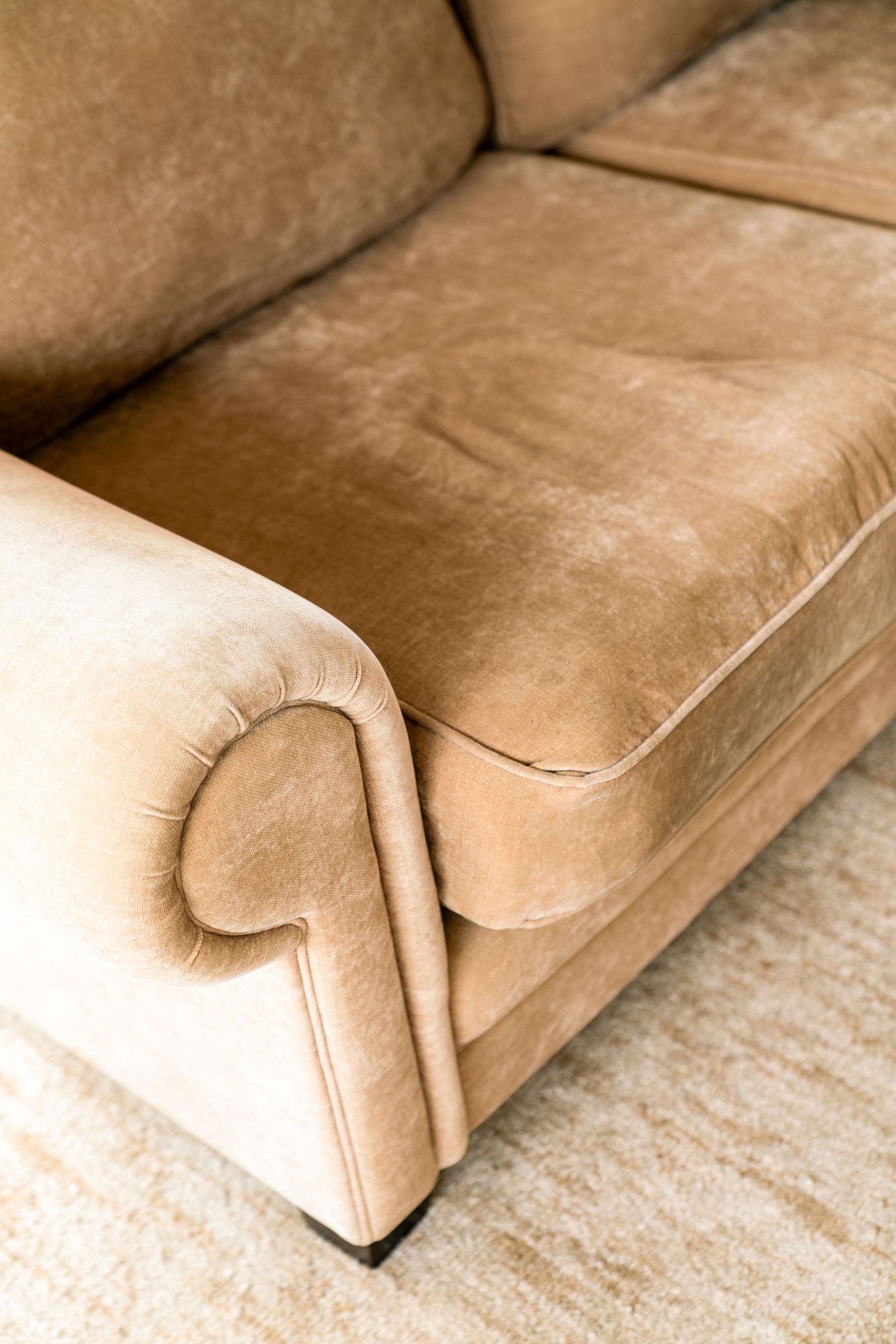 Close-up details of beige suede couch cushions showing texture and stitching.