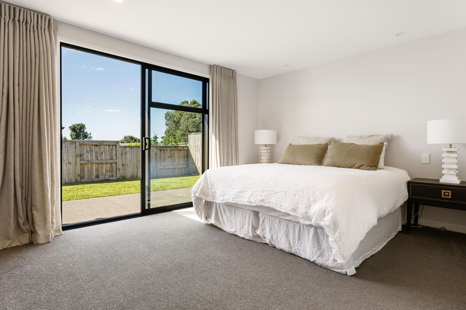 Modern bedroom interior with large windows offering panoramic views of green outdoor landscapes and natural light.