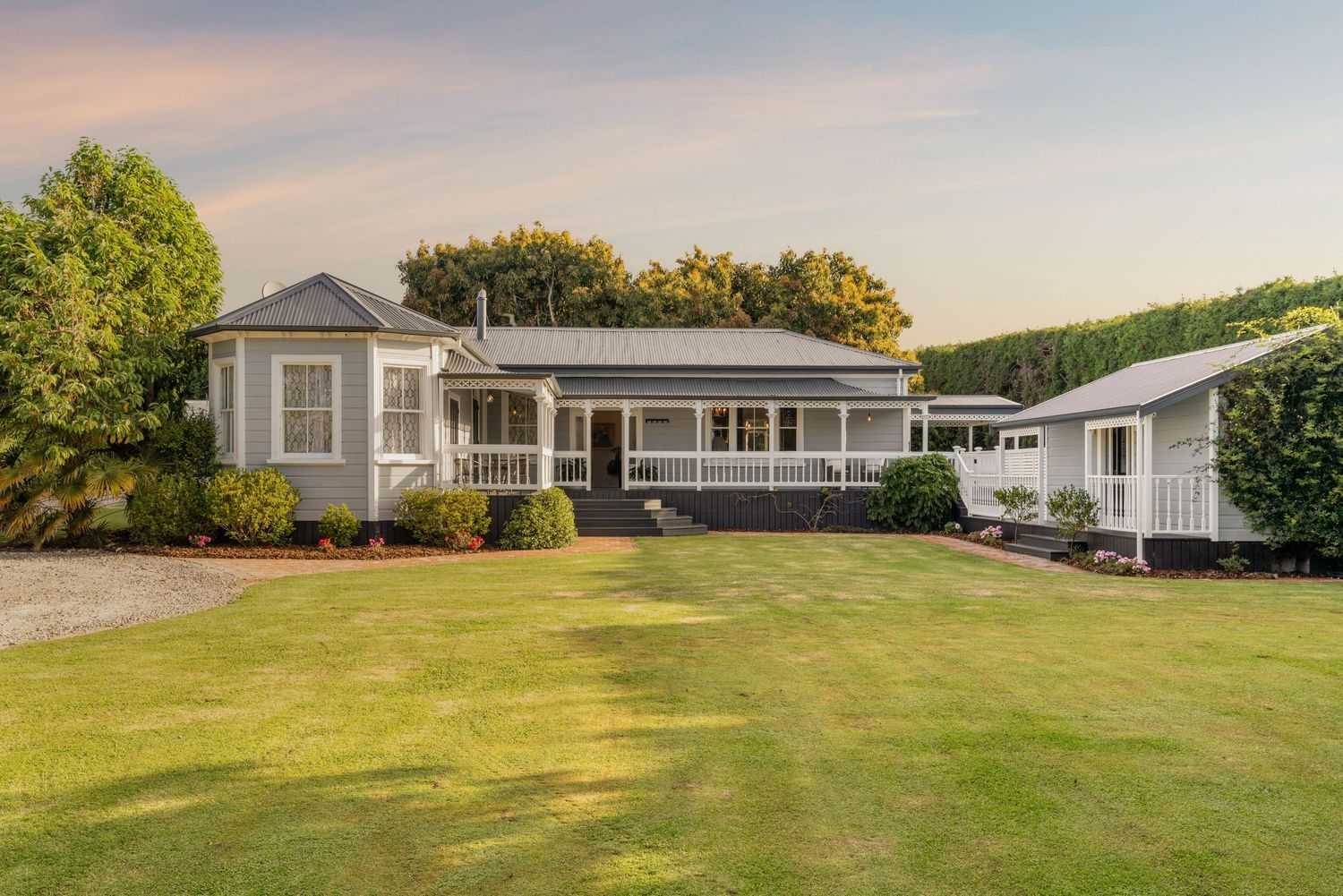 Panoramic view of a modern ranch-style home with white exterior and expansive green lawn.