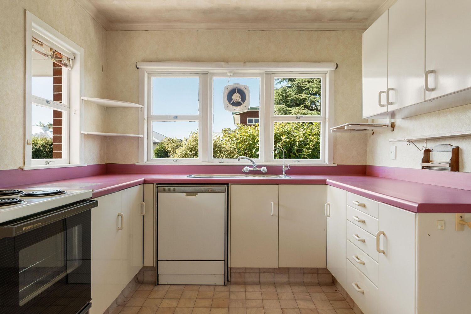 Panoramic view of a modern white kitchen with pink countertops and ample cabinet storage.