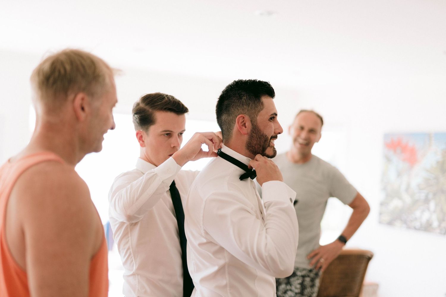 A group of people laughing and getting ready together in a bright room during a casual gathering.