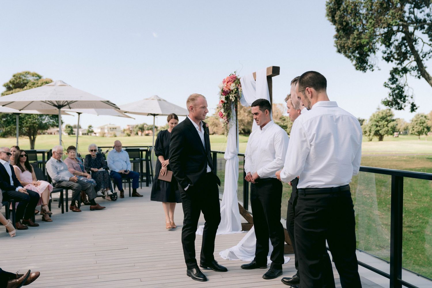 Outdoor wedding ceremony setup with guests seated in rows on a grassy lawn.