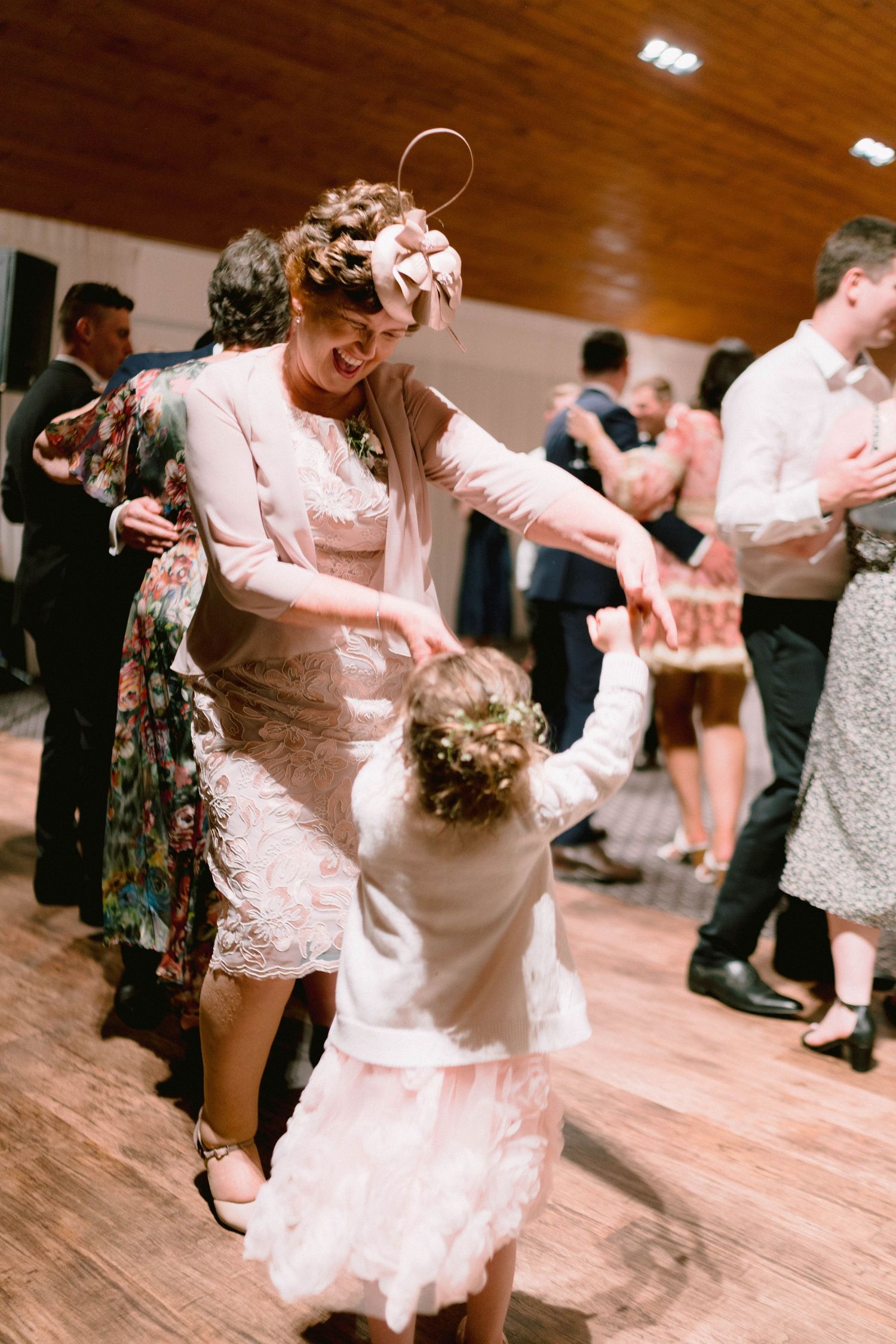 A heartwarming dance moment between guests at a wedding reception on a wooden dance floor.
