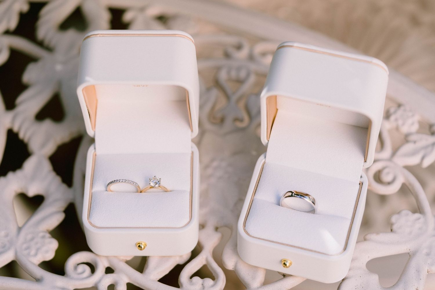 White engagement ring boxes with delicate floral details arranged in a row on linen surface.