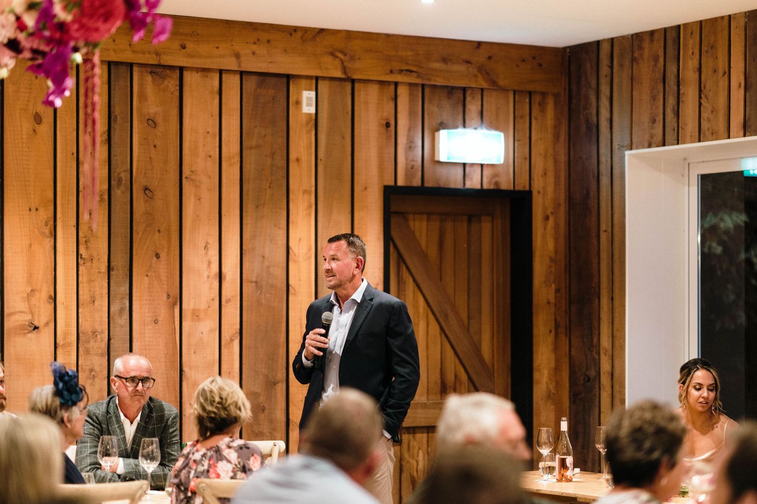 Reception venue with rustic wood paneling decorated with vibrant magenta floral accents.
