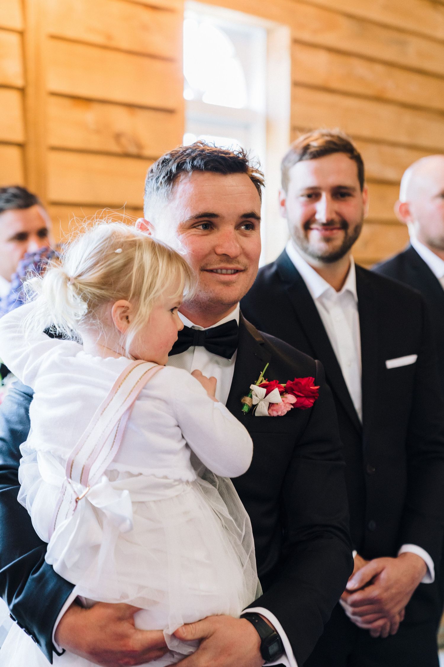Wedding celebration moment with formal attire and young child in white dress.