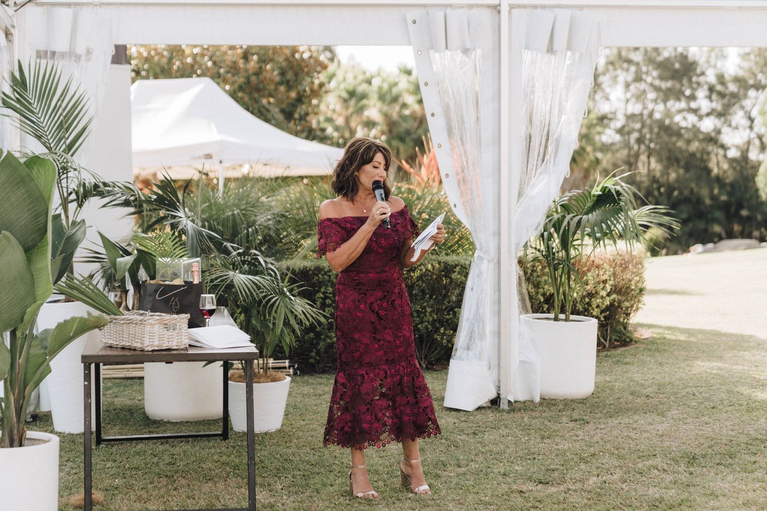 White tent reception area decorated with flowing curtains and tropical plants.