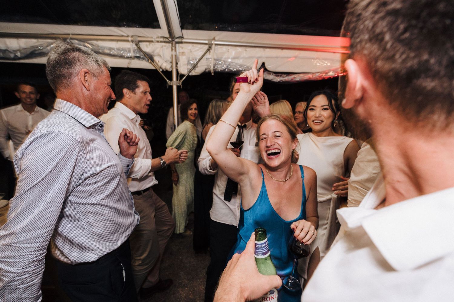 Lively dance floor moments captured at a joyful wedding reception under dimmed lighting.