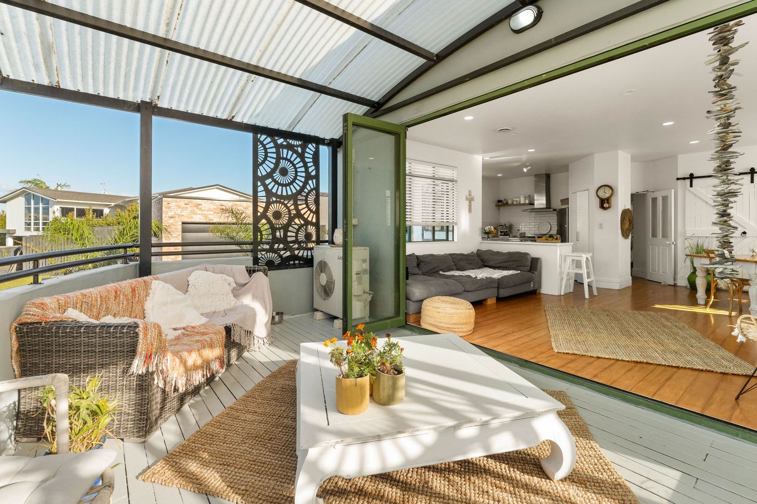 Modern coastal living room with indoor-outdoor flow featuring wicker furniture and ocean views.