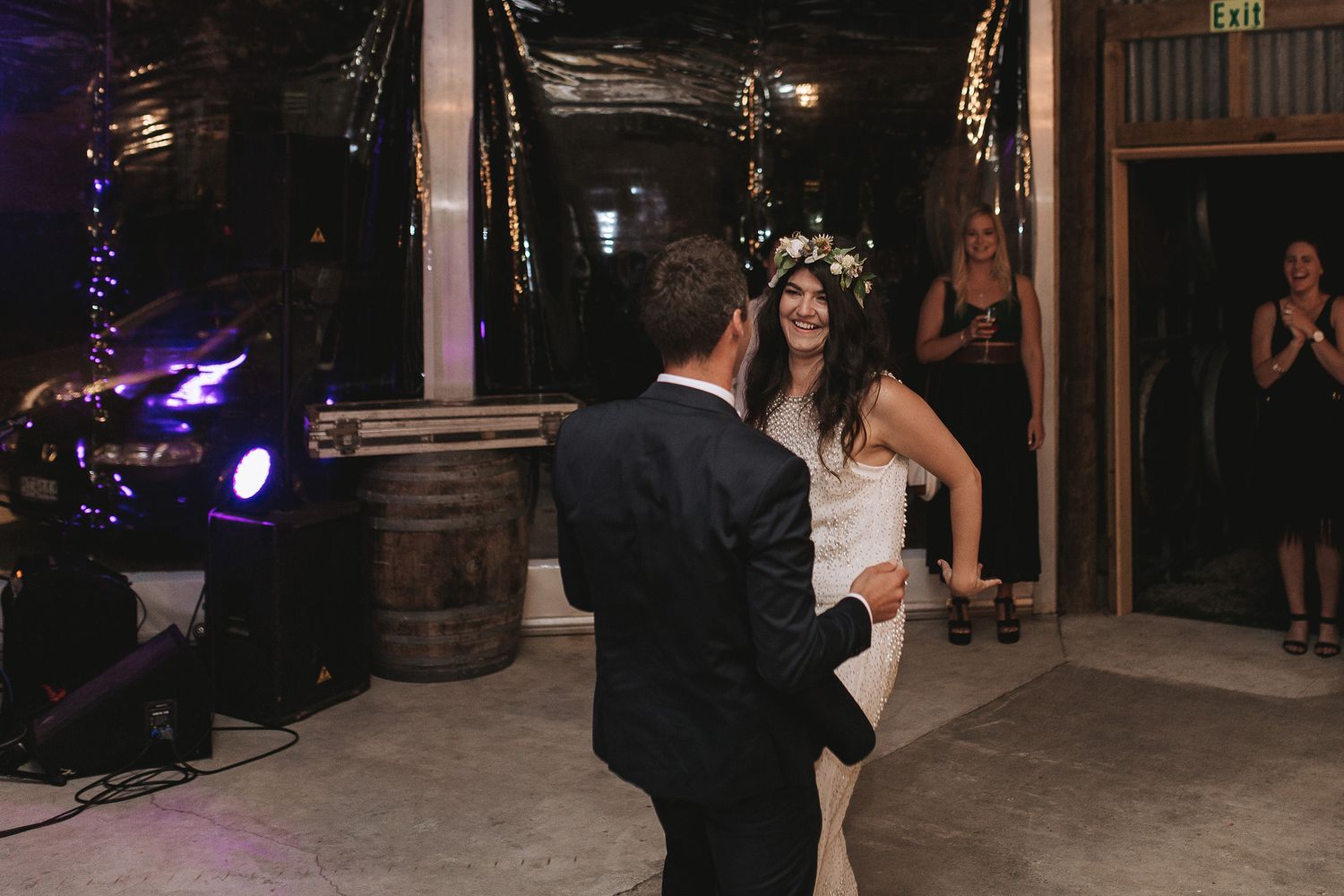 A couple shares a dance together on the dance floor at a festively decorated nighttime wedding venue.