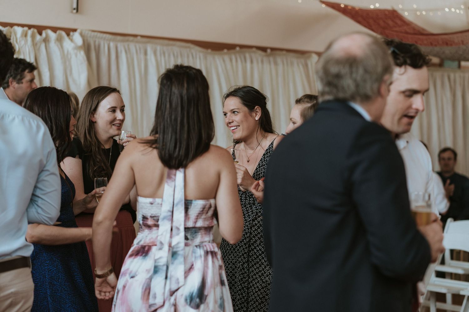 Groups of guests mingle and socialize during an upscale indoor event with a bright, elegant atmosphere.