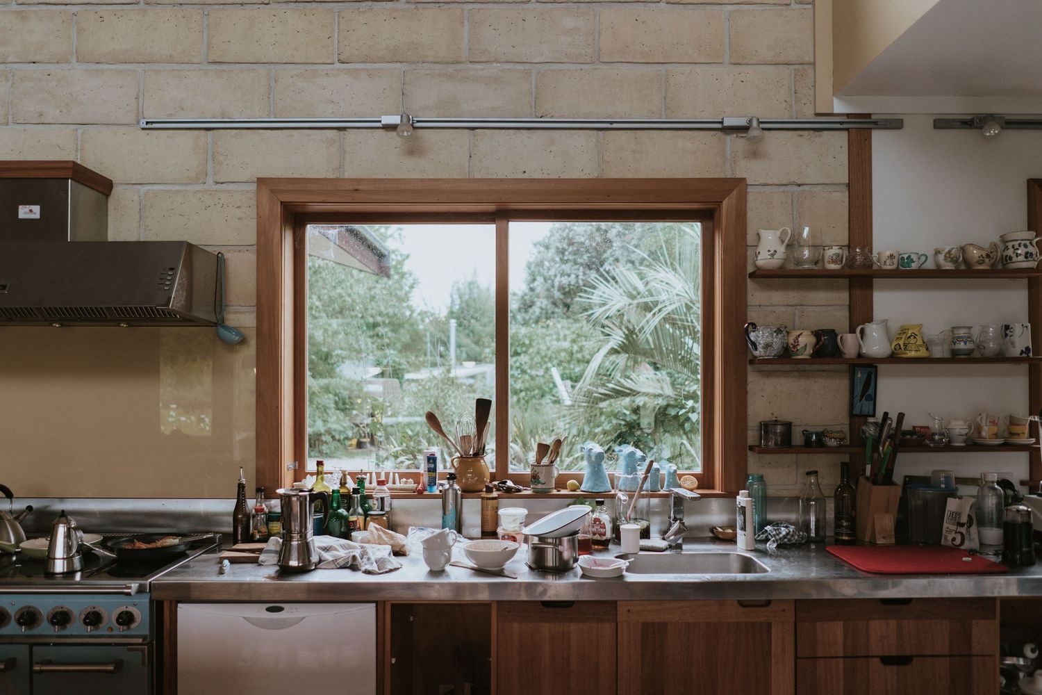 Panoramic view of a simple farmhouse kitchen with butcher block counters and wooden cabinets against an off-white wall.